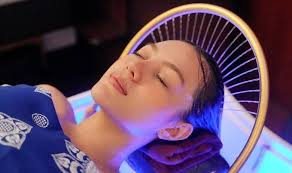 A guest relaxing with eyes closed under the head spa's arched water canopy