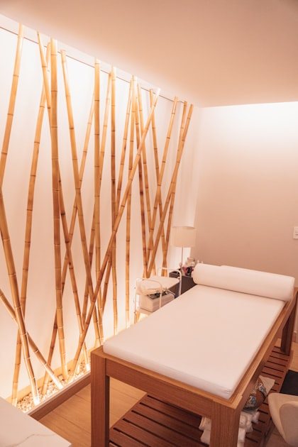 A calm treatment room at Desert Zen: a white-draped massage table beside a wall of tall natural bamboo